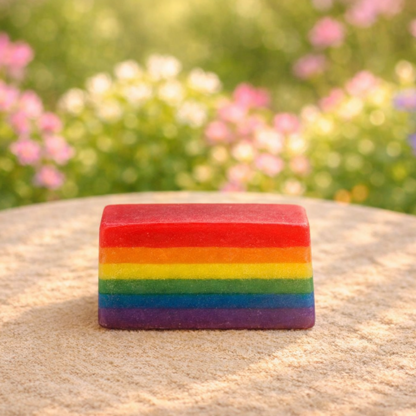 Rainbow-colored soap bar on a rock with a blurred floral background