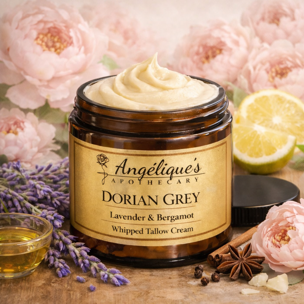 A jar of Angelique's Apothecary Dorian Grey Lavender & Bergamot Whipped Tallow Cream, styled with lavender sprigs, a lemon slice, star anise, cinnamon, and pink peony flowers on a wooden surface.